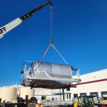 IRH machinery moving crew member looks on as production equipment is loaded into the manufacturing facility.