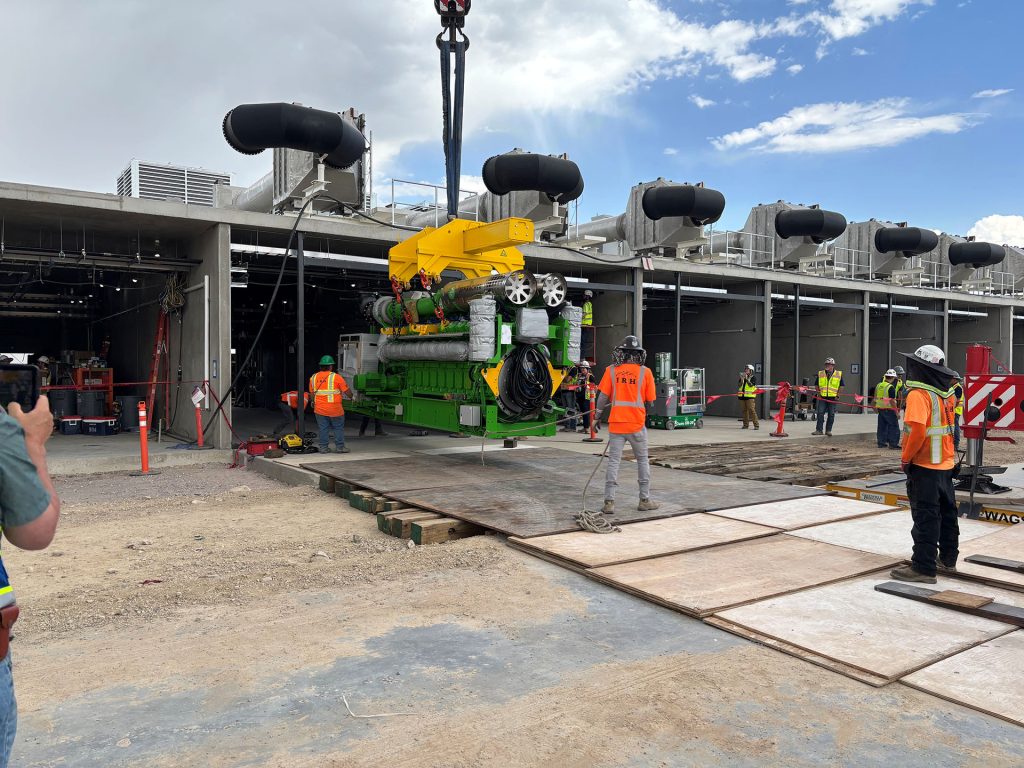 IRH crew member holding a tag line while a 275-ton crane lifts a generator.