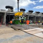 IRH crew member holding a tag line while a 275-ton crane lifts a generator.