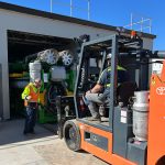 A forklift driver and spotter guiding a generator into place.